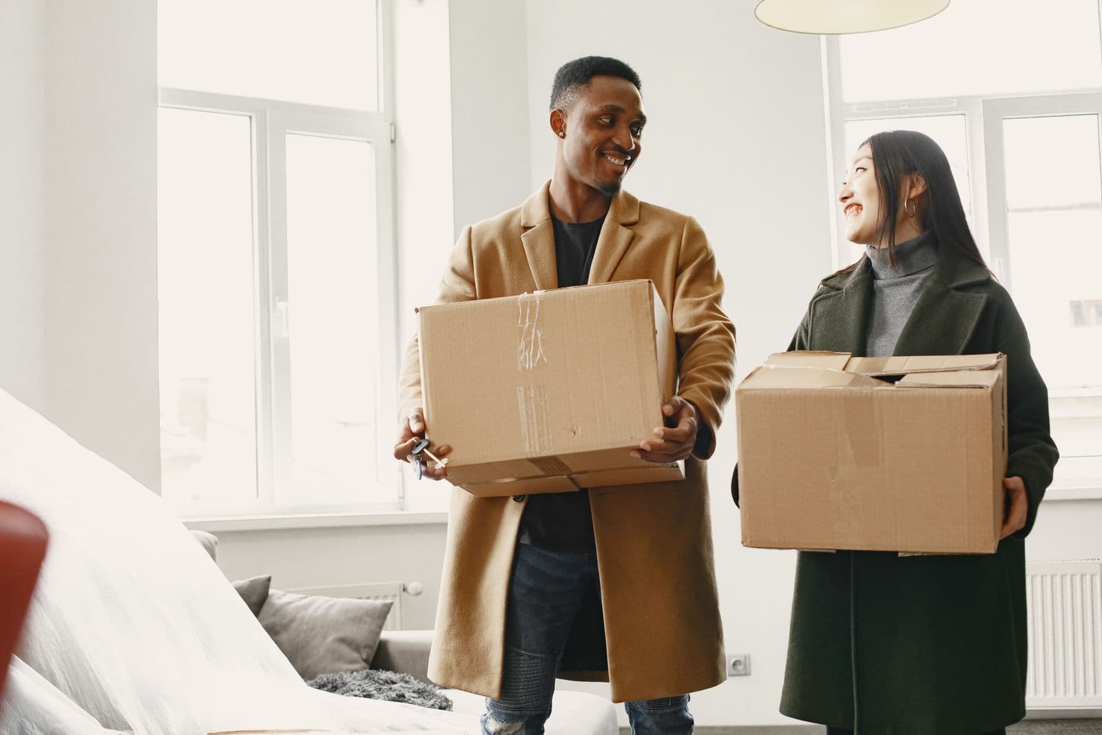 A couple carrying cardboard boxes into their new home