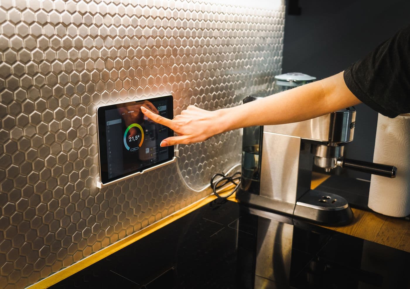 A hand adjusting a smart heating control mounted on a kitchen wall