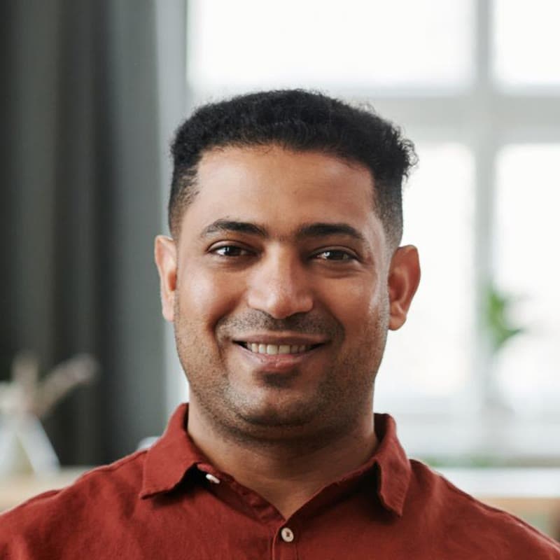 A smiling man in a red shirt at home